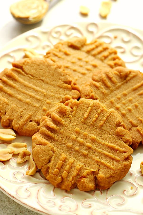 Side shot of four peanut butter cookies on a plate.