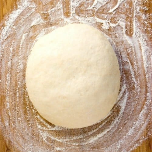 Pizza dough on a wooden board.