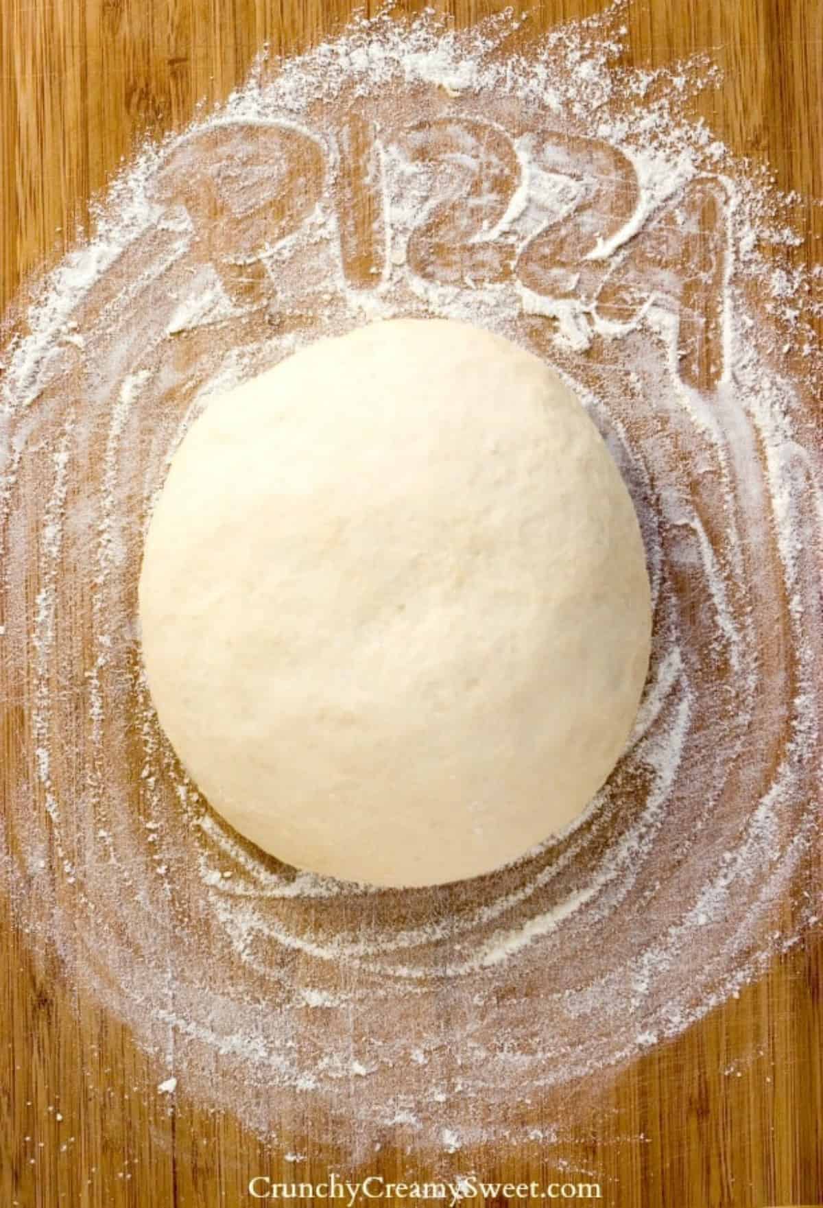 Pizza dough on a wooden board.