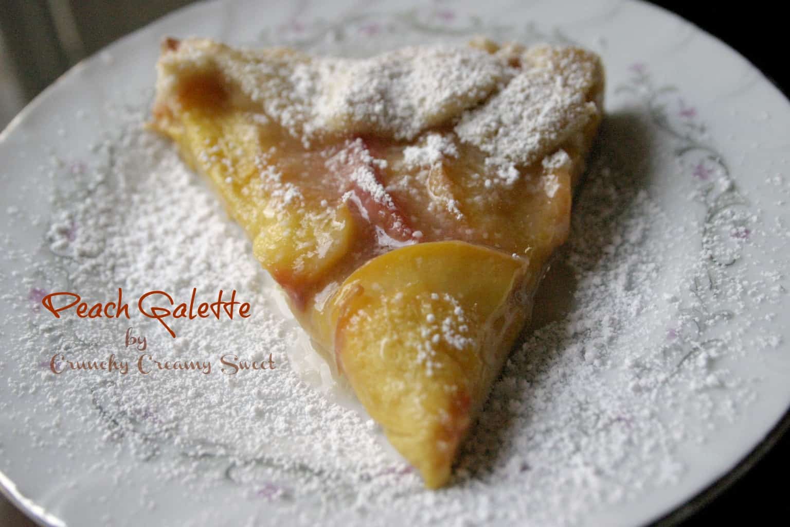 Side shot of peach galette slice on white plate.