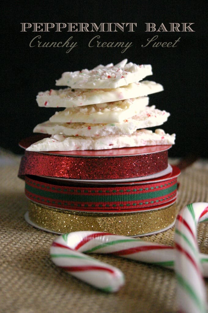 Pieces of peppermint bark stacked up on top of holiday ribbon spools.