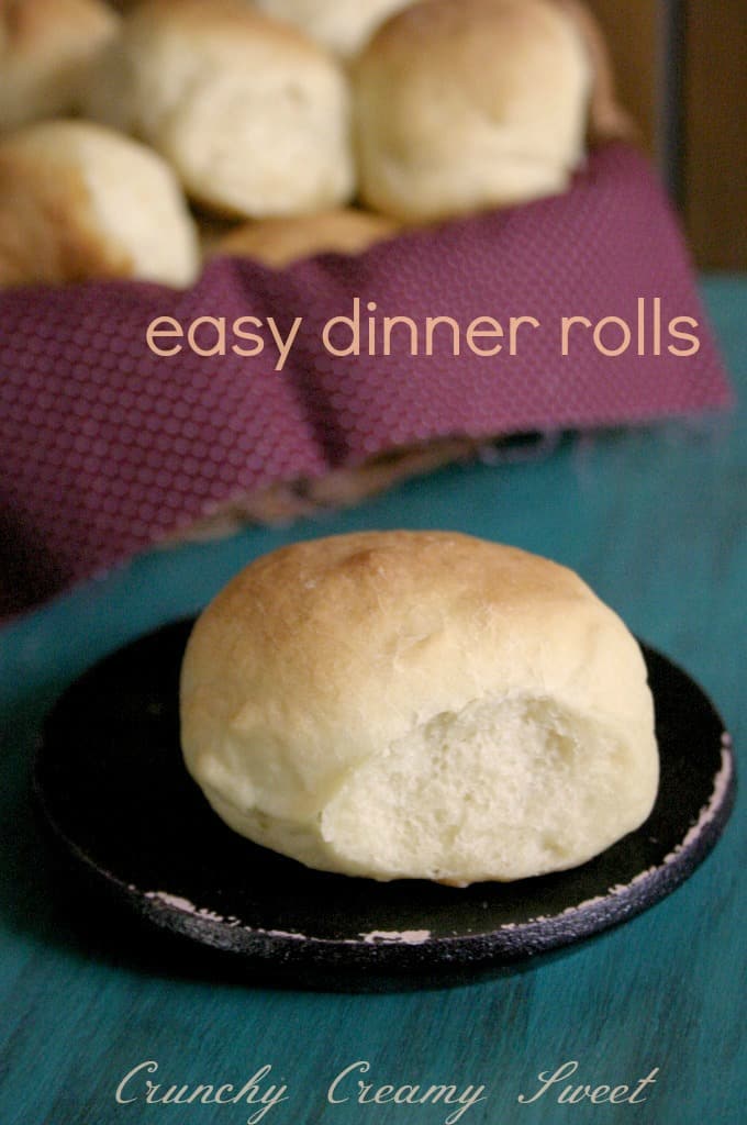 Side shot of one dinner roll on black plate.