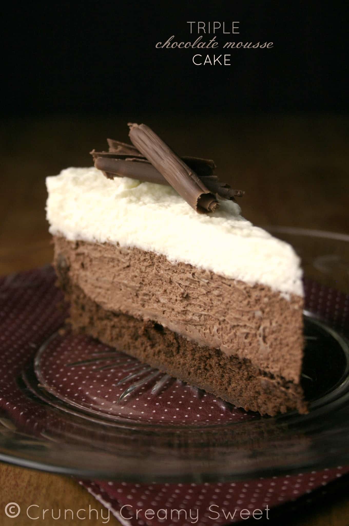 Side shot of a slice of triple chocolate mousse cake on glass plate.