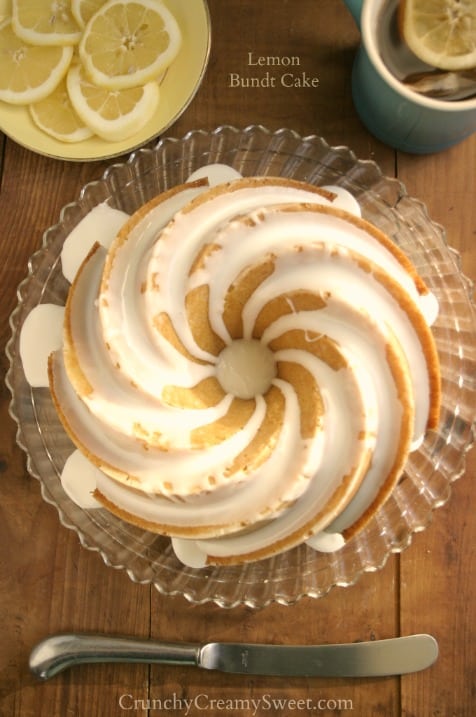 Overhead shot of lemon bundt cake with white glaze on cake stand.