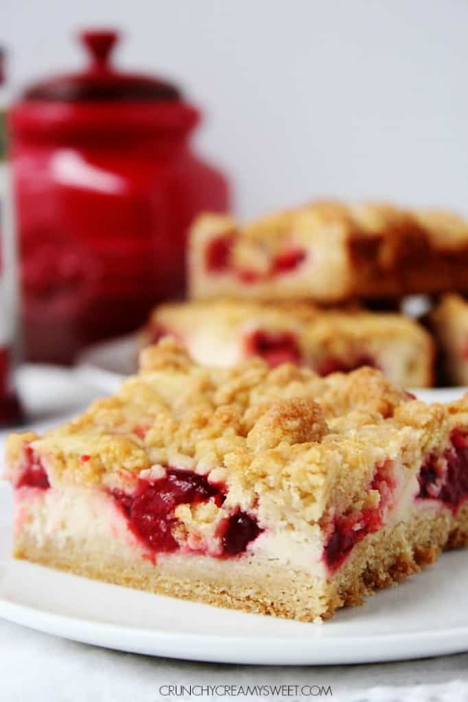 Side shot of one strawberry crumb bar on white plate.