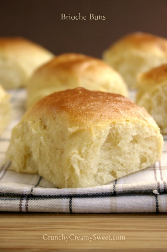 Side close up shot of brioche bun on kitchen towel, with others in the background.