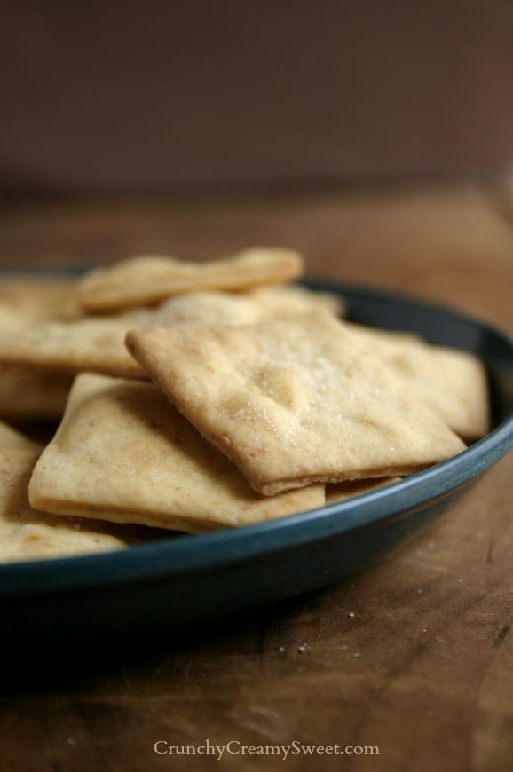 Close up shot of homemade crackers on plate, on wooden board.