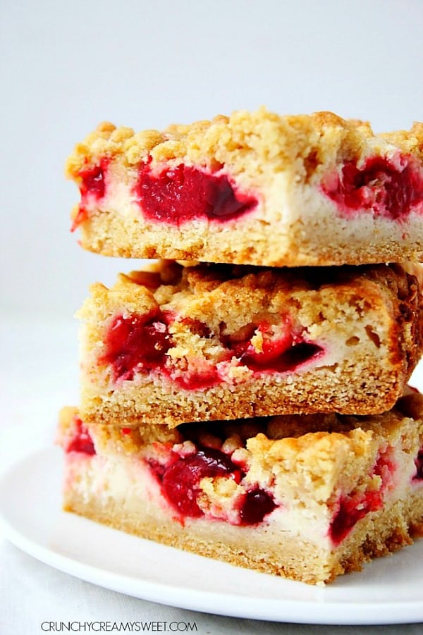 Strawberry Pie Sour Cream Crumb Bars - The best crumb bars you'll ever have! Creamy sour cream filling and sweet strawberry pie filling makes them irresistible! Strawberry Pie Crumb Bars stacked up on white plate.