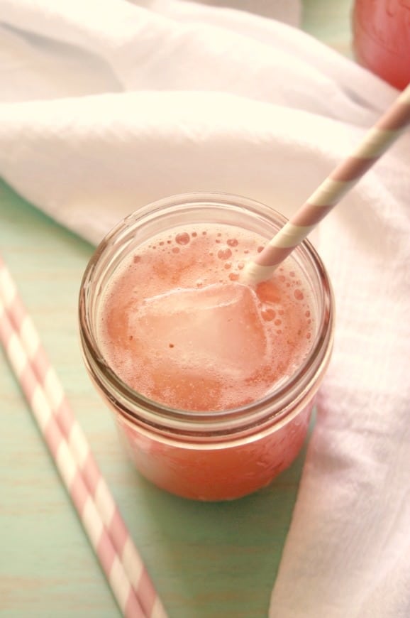 Overhead shot of strawberry agua fresca in glass jar with straw.