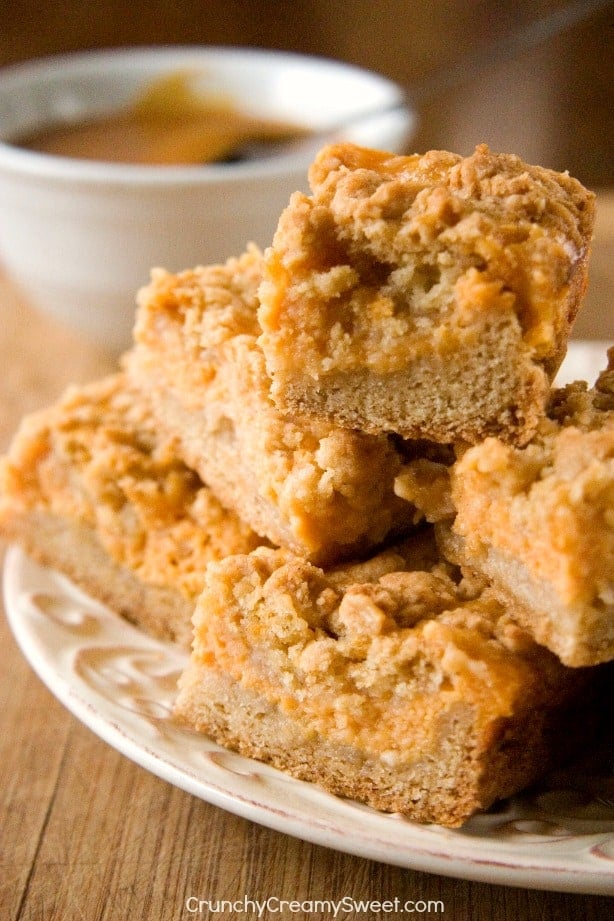 Side shot of pumpkin spice crumb bars stacked up on each other on a plate.