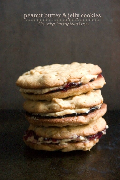 Side shot of peanut butter jelly sandwich cookies stacked up on each other.
