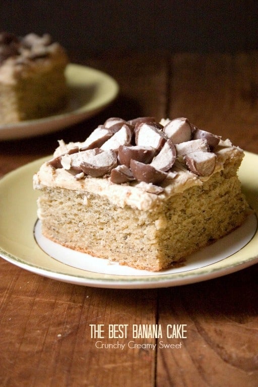 Side shot of banana cake piece with Whoppers on top on plate.