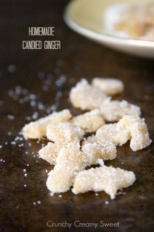 Side shot of candied ginger coated in sugar on baking sheet.