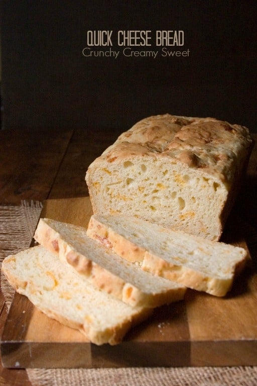 Side shot of cheese bread with few slices down on cutting board.