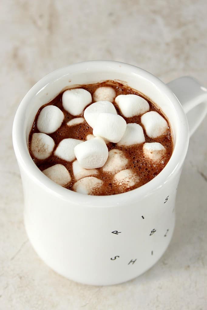 Homemade hot chocolate with mini marshmallows in white mug.