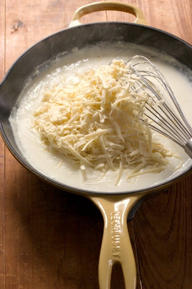 White sauce with Pepper Jack cheese on top in skillet.