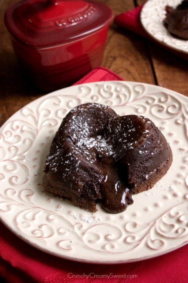 Side shot of heart-shaped molten lava cake with gooey center on plate.