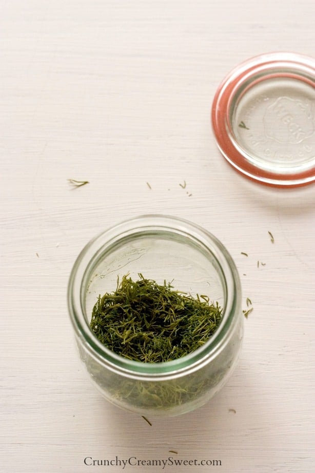 Side shot of dried herbs in a weck jar, lid next to it.