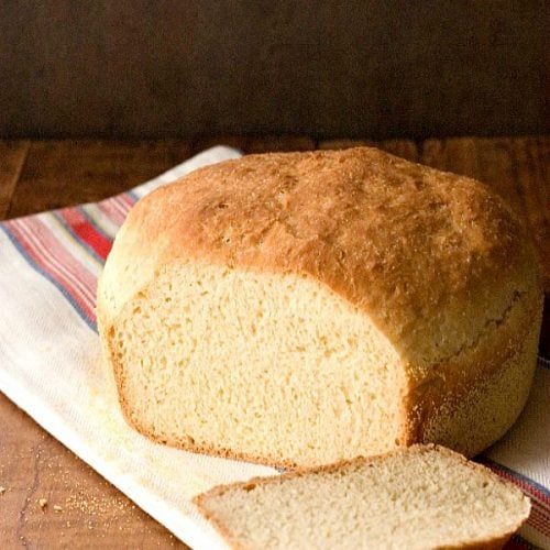 English Muffin Bread on kitchen towel, with one slice cut.