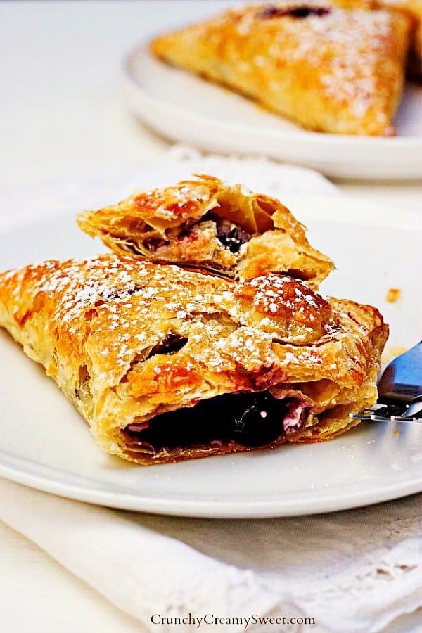 Close up on turnover with cut off piece, blueberry filling visible.