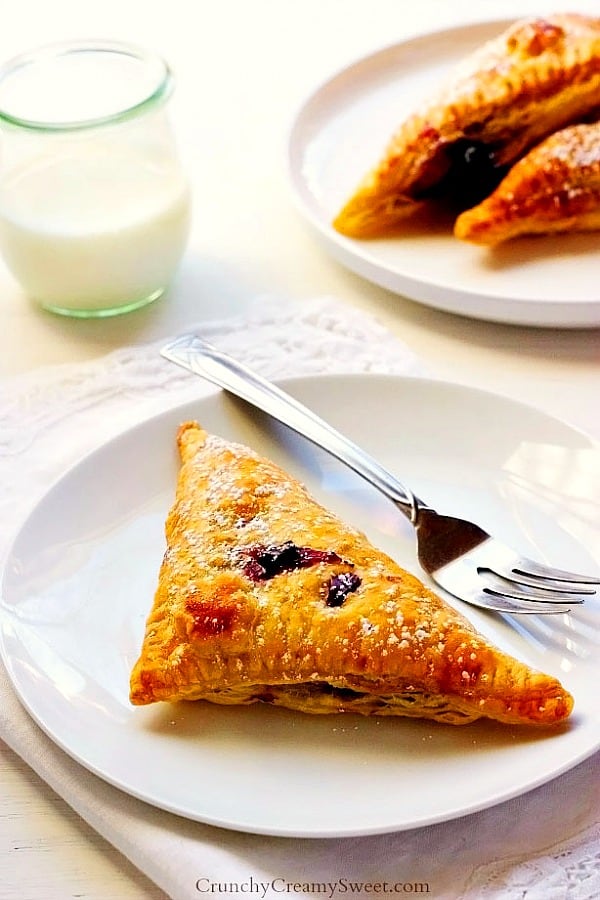 Turnover pastry on white plate with fork.