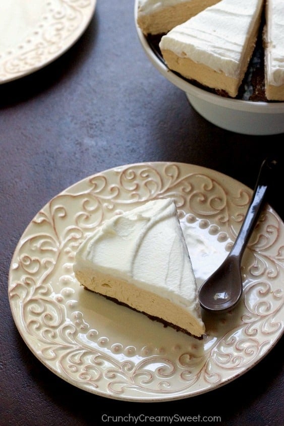 Side shot of a slice of no-bake peanut butter cheesecake on plate with spoon.