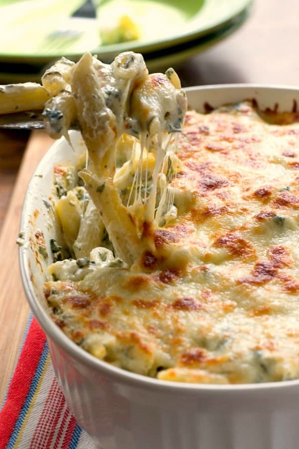Cheesy Spinach Dip Chicken Pasta - your new favorite dinner! Spinach dip and pasta get together to create one cheesy and creamy dish! You need to make it! Spinach Dip Chicken Pasta in a casserole dish.