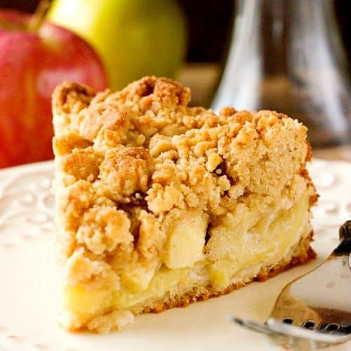 Apple cake with crumb topping on plate.