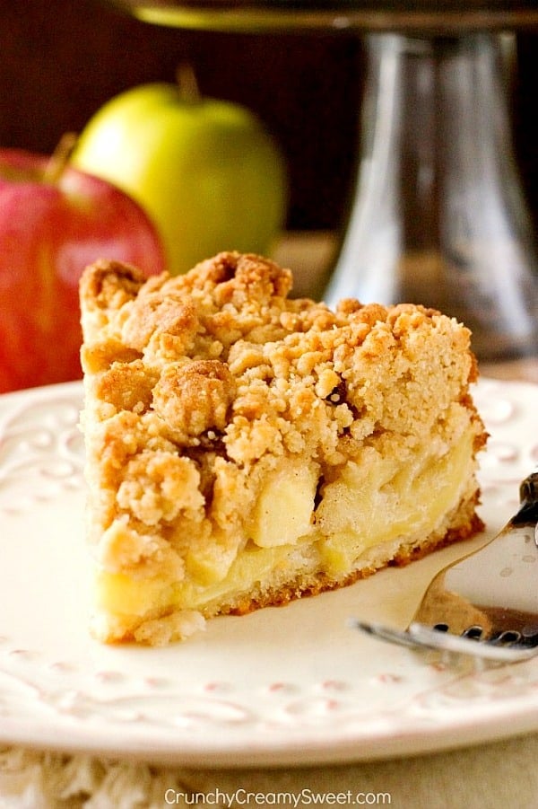 Apple crumb cake slice on white plate with fork.