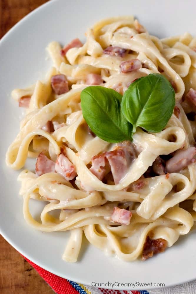 Overhead shot of pasta carbonara with basil leaves on top.