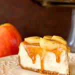 Slice of cheesecake with apples and caramel, on plate.