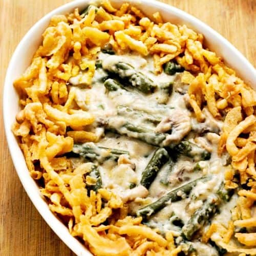 Green bean casserole in white oval baking dish.