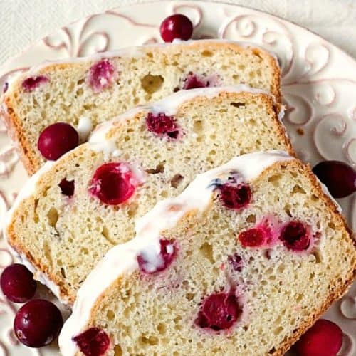 Cranberry Bread with glaze sliced on a plate.