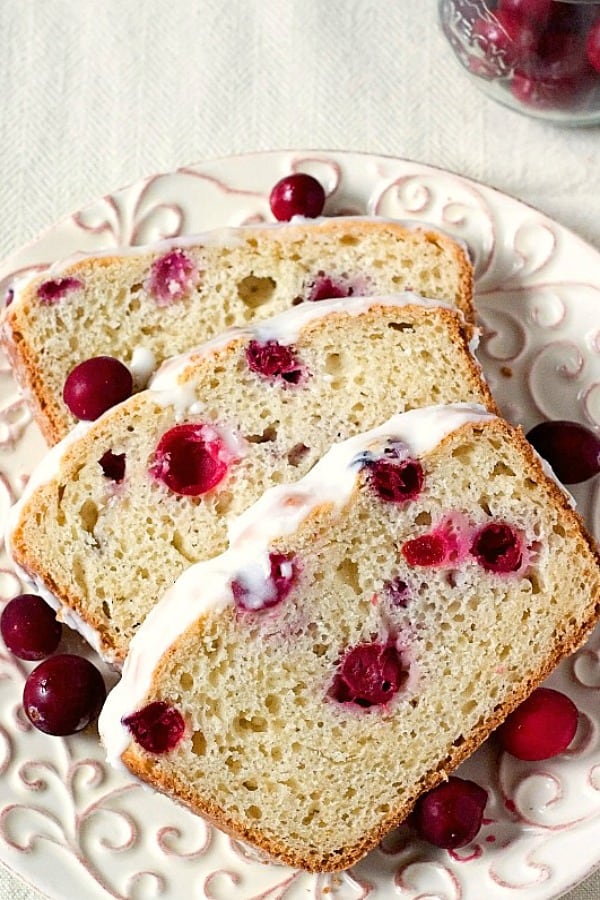 Cranberry Bread with glaze sliced on a plate.
