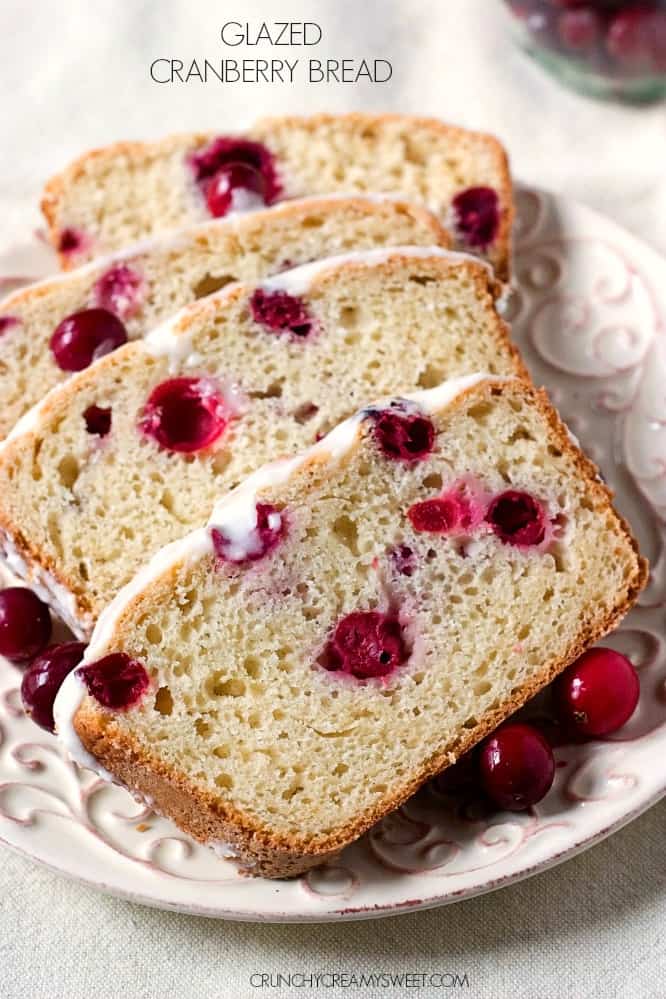 Side shot of four slices of cranberry bread with glaze on white plate.