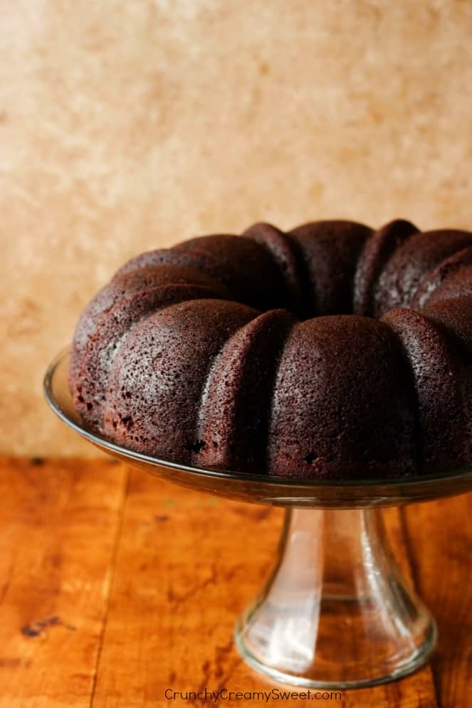 Side shot of chocolate bundt cake on glass cake stand.