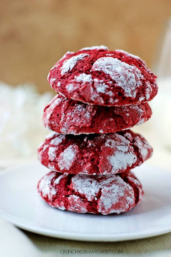 A stack of four red velvet cookies on white plate.