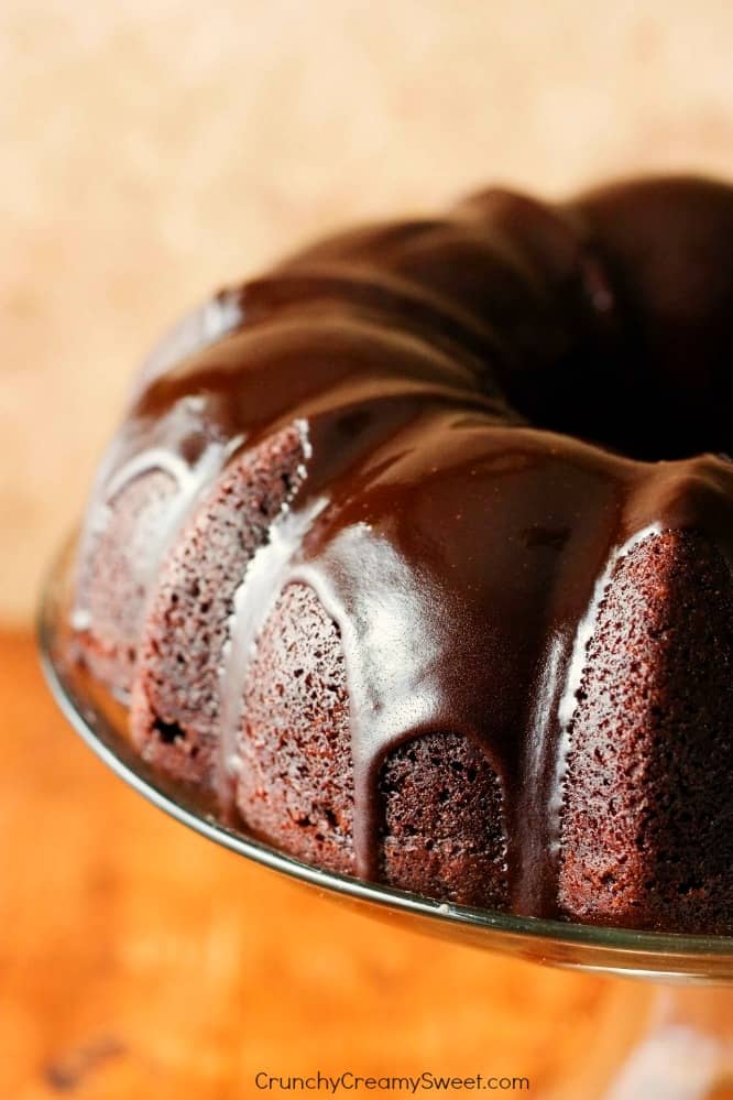 Side shot of chocolate bundt cake with chocolate glaze on cake stand.