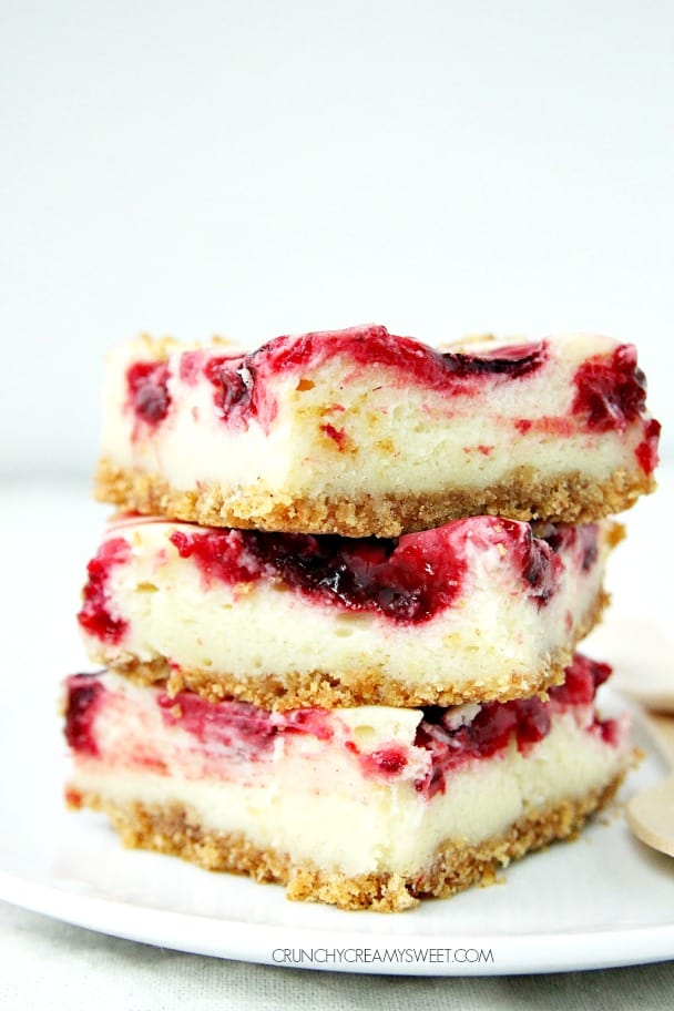 Lemon Raspberry Cheesecake Bars crunchycreamysweet.com Side shot of three pieces of lemon raspberry cheesecake bars stacked up on each other.
