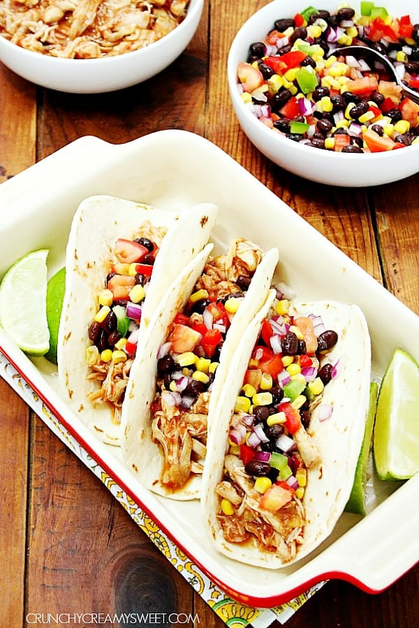Slow Cooker Chicken Tacos - only 5 minutes of prep is required for this easy Mexican dish! Place everything in slow cooker, set it and let it do it's magic! Three tacos with chicken in baking dish.
