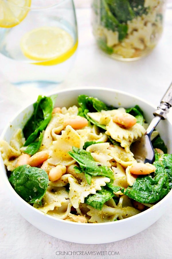 Side shot of pasta and spinach in white bowl.