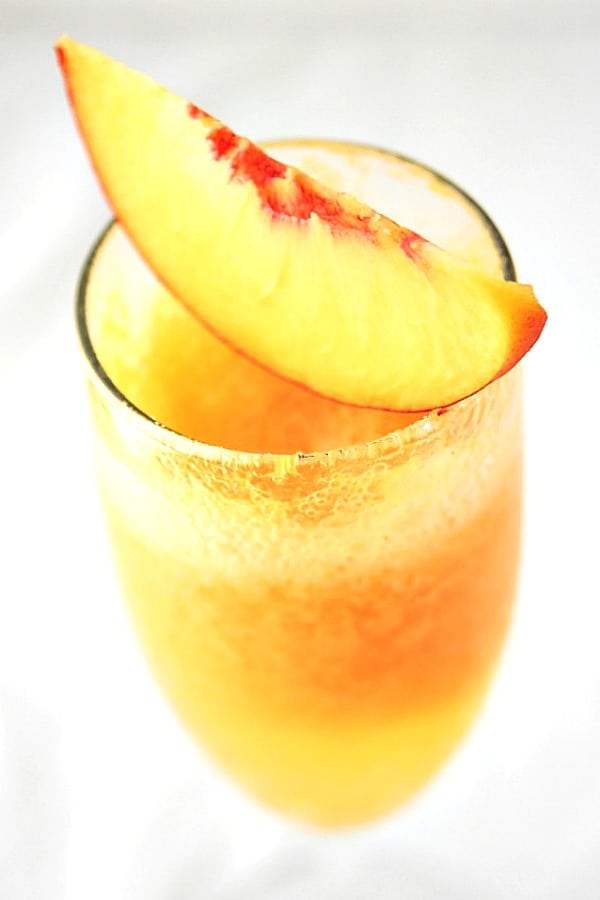 Frozen Peach Bellini - jazz up your sparkling wine with a frozen peach puree for a fun summer drink that is full of bubbles and sweet peaches! Frozen Peach Bellini in a glass.