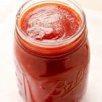 Side shot of BBQ sauce in a glass jar.