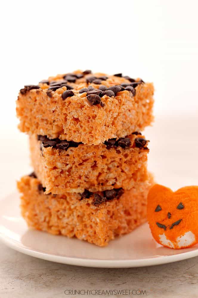 Pumpkin Spice Rice Krispies Treats - super fun Halloween treats that use no additional coloring die besides the orange pumpkin marshmallow Peeps! Addition of pumpkin spice makes them a great fall treat for kids and adults! Pumpkin Spice Rice Krispies in a stack on white plate.