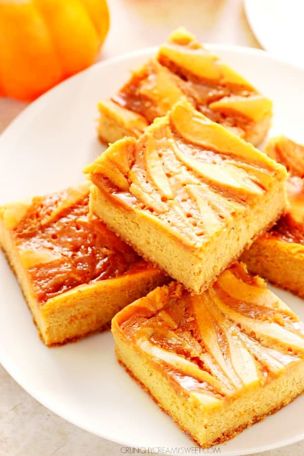 Pumpkin Cheesecake Bars - sweet and creamy cheesecake bars with pumpkin, spice and caramel swirl. A must make dessert this season! Pumpkin Cheesecake Bars on a white plate.