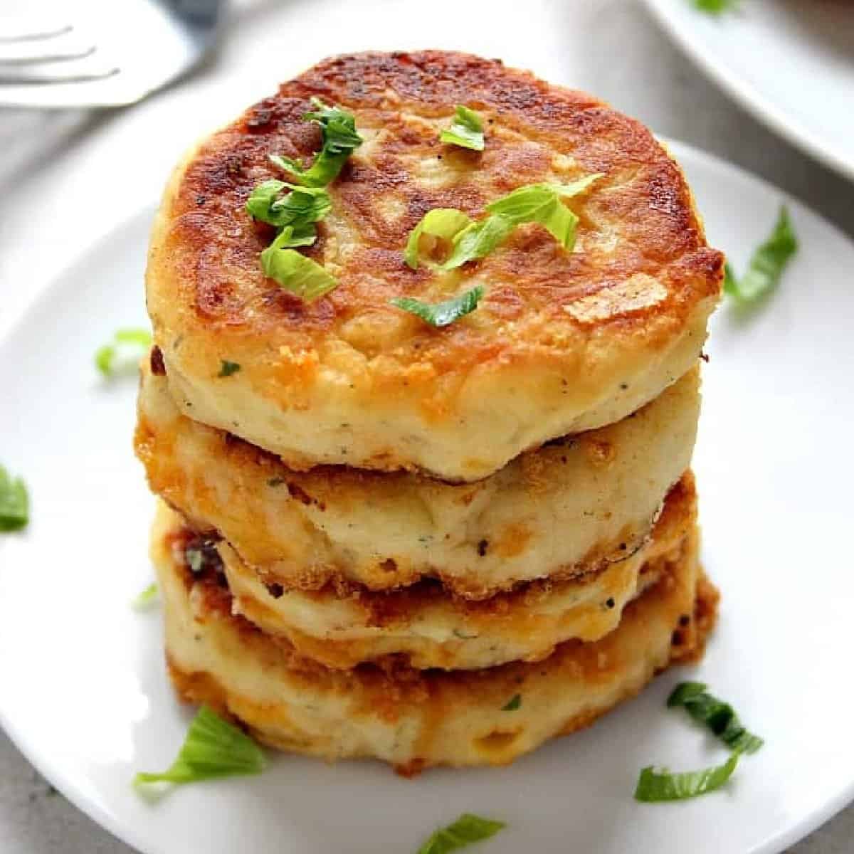 Square photo of a stack of potato cakes on a white plate.