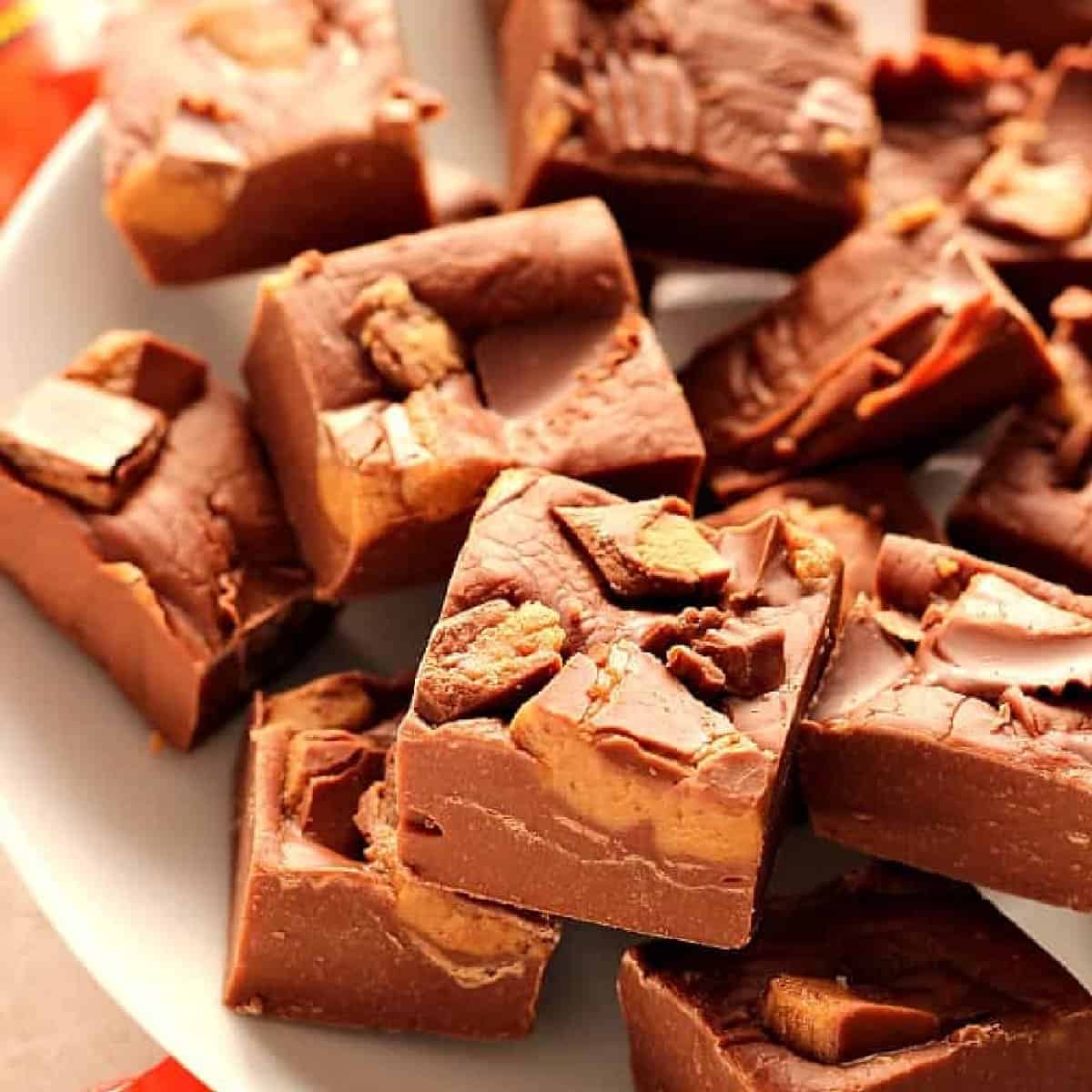 Squares of Reese's peanut butter cups fudge on a white plate.