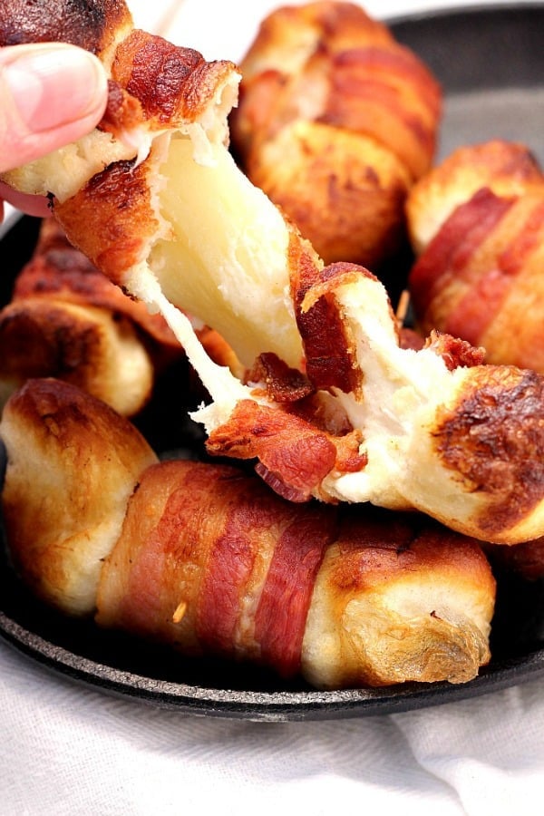 Bacon wrapped cheese bombs in small cast iron skillet.