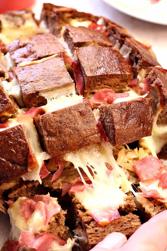 Easy Cheesy Reuben Pull Apart Bread - this one is EPIC! Pumpernickel bread filled with Thousand Island dressing, sauerkraut, corned beef and lots of cheese! Pull apart bread Reuben style! 