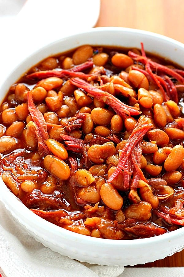 Slow Cooker Baked Beans - comfort food classic made easy in the slow cooker with dried beans (no cans!). Use a leftover ham bone or bacon for best flavor. This recipe is a family favorite! Baked beans in white bowl.
